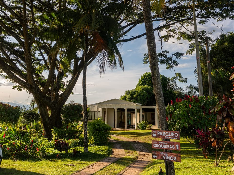 Entrada de Finca Termópilas con señales hacia el alojamiento, el jardín de orquídeas y los vinos